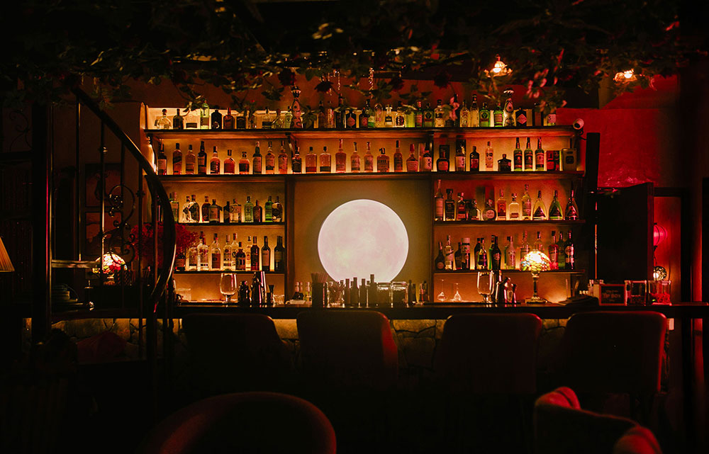 The glowing moon behind the bar at SpeakEasy Moon Bar